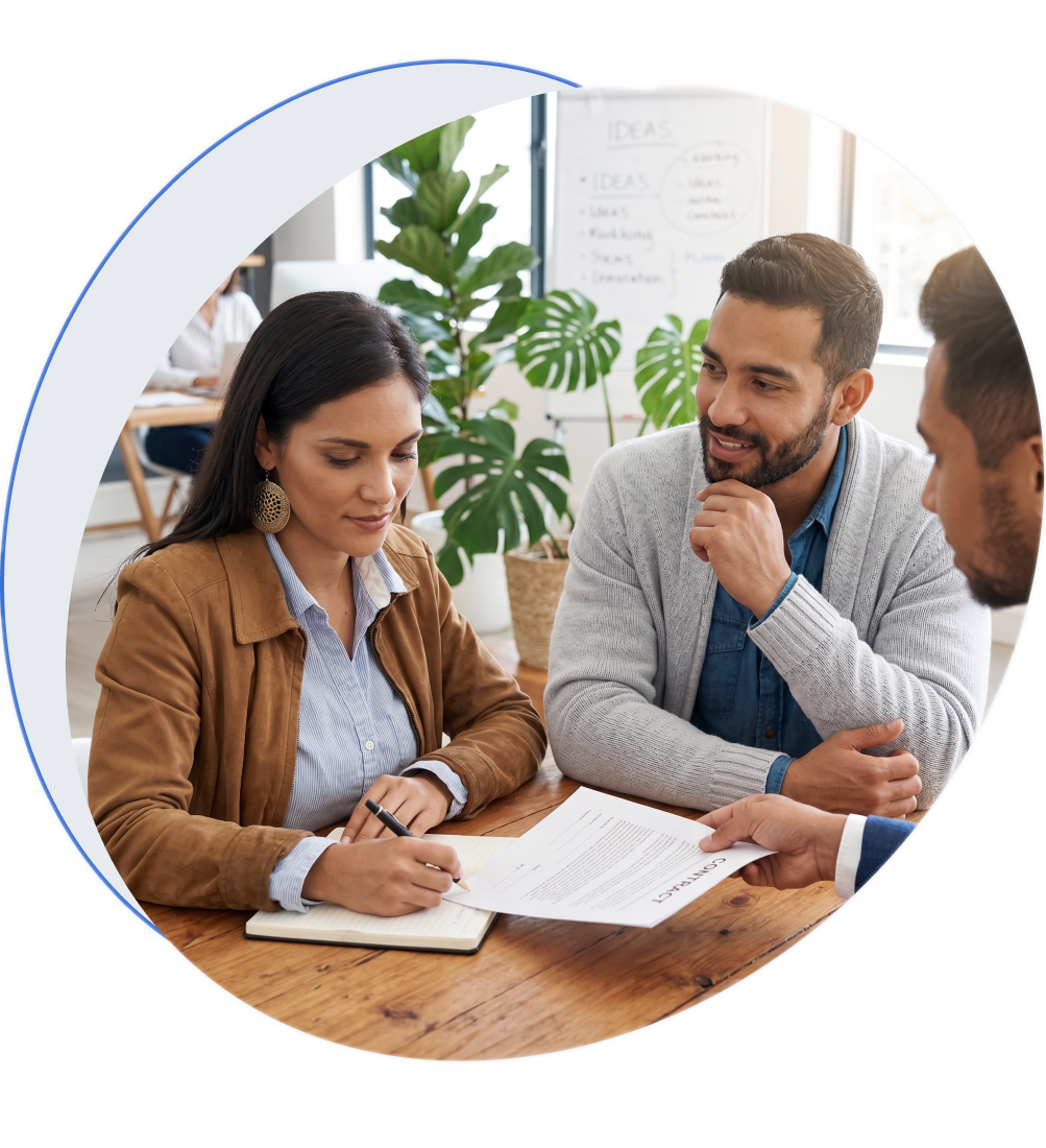 Tres personas revisando un contrato en una mesa de trabajo